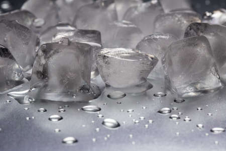 Ice cubes on a reflecting table with drops of water on a black backgroundの写真素材