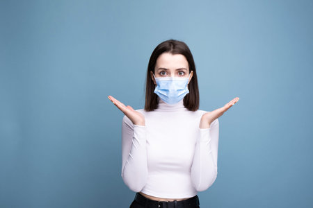 A woman with symptoms of a cold and headache holds in her hand in the studio on a blue background