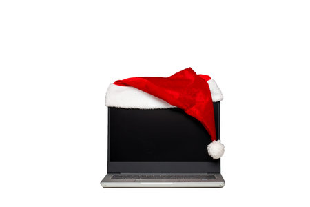 Laptop on a white isolated background. A hat of santaclaus lies on a laptop. The end of the working...