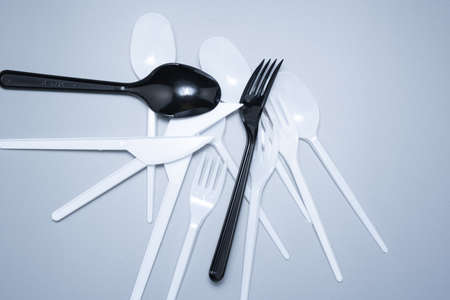 Scattered plastic forks knives spoons on a gray background close-upの写真素材