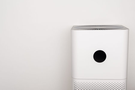 Indoor air purifier of white color close-up on a white background. Dust and allergy cleaner in the...