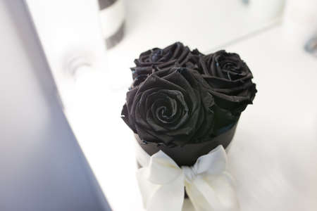 Black roses in a box with a white bow on a black backgroundの写真素材