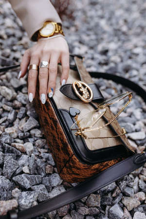 Stylish womens handbag with glasses and a girls hand on a background of stones close-up.の写真素材