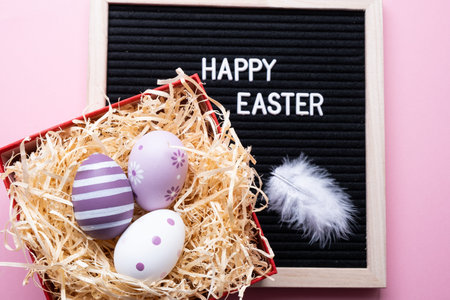 Happy easter. Easter eggs with a feather on a pink background.