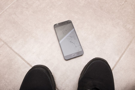 The black smartphone fell out of my hands and the screen crashed to smithereens.の写真素材
