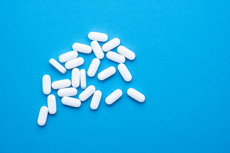 White pills on a blue background close-up.