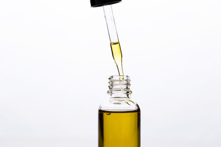 Massage oil in a glass bottle with a pipette on a white isolated background.