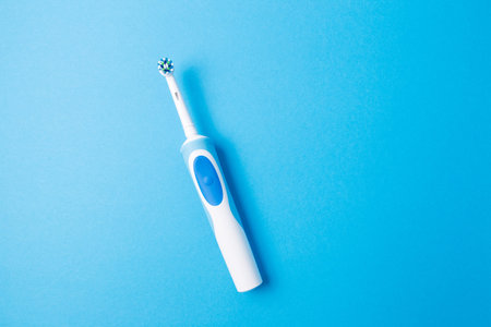 Smart electric toothbrush on a blue isolated background.