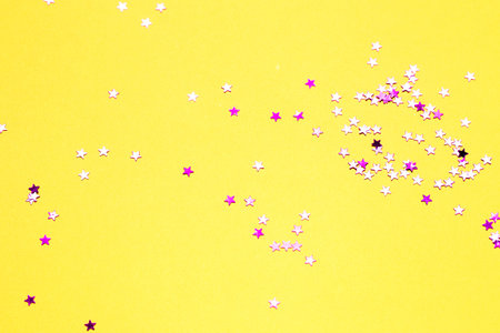 Closeup asterisks sprinkled on a yellow isolated background. View from above.