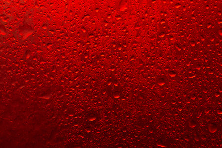 The texture of a water drop on a red background close-upの写真素材