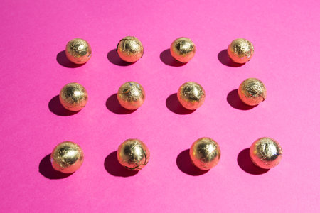 Chocolates in a multi-colored foil on a pink backgroundの写真素材