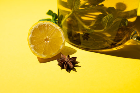 Green tea with lemon mint and star anise on a yellow background.の写真素材