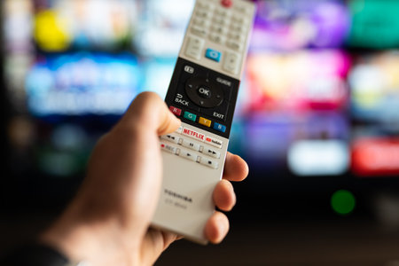 Tarragona, Spain - May 20 2023: A man or woman presses the Netflix button on the TV remote control.のeditorial素材