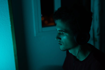 Portrait of a gamer in headphones in neon blue light.