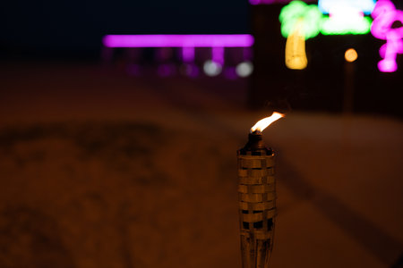 A burning torch at night on the beach against the backdrop of a bar close-up.の写真素材