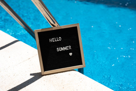 Hello summer text on chalkboard on pool background on summer sunny day.の写真素材