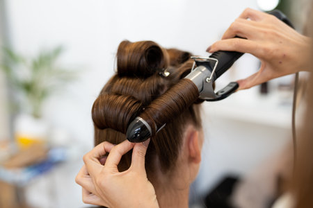 The hairdresser curls the models hair. Curling iron for curling hair close-up.の写真素材
