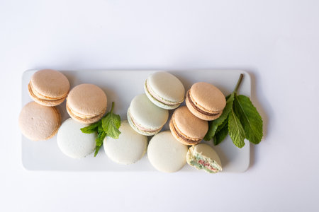 Macaroons of different colors with sprigs of mint on a white background.の写真素材
