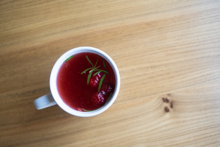 Raspberry tea in a white mug on a wooden table.の写真素材