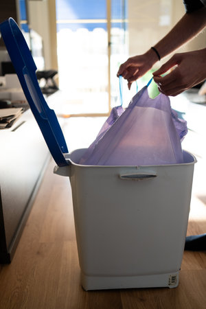 A man takes out a trash bag from a bin. Maintaining cleanliness and household cleaningの写真素材