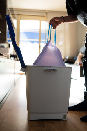 A man takes out a trash bag from a bin. Maintaining cleanliness and household cleaningの写真素材