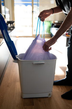 A man takes out a trash bag from a bin. Maintaining cleanliness and household cleaningの写真素材