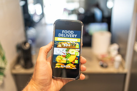 Male hands holding phone with food delivery app on screen against background of room in house
