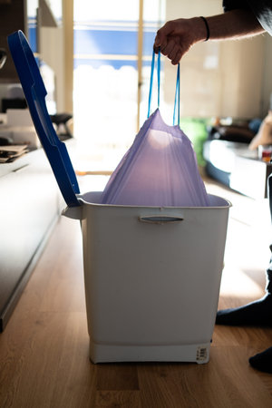A man takes out a trash bag from a bin. Maintaining cleanliness and household cleaning