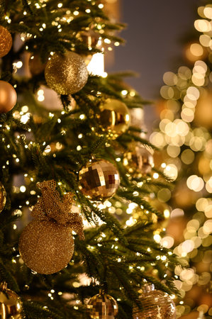 Close-up of a beautifully decorated Christmas tree with golden ornaments, sparkling lights, and festive bokeh in the background.の写真素材