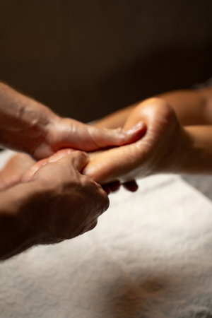 Close-up of a professional foot massage session in a spa, therapist gently pressing the sole with hands, promoting relaxation, circulation, and wellness in a calm environment.の写真素材
