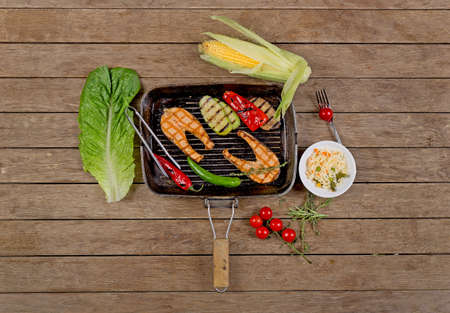 grilled salmon with vegetables, rice, corn on wooden background top viewの写真素材