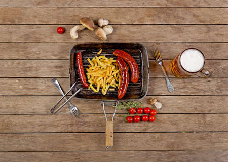 potatoes with sausages and beer in the pan on wooden background top viewの写真素材