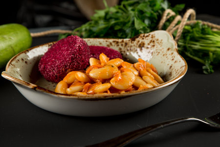Boiled beans and beetroot patties in a plate, on a wooden table top view