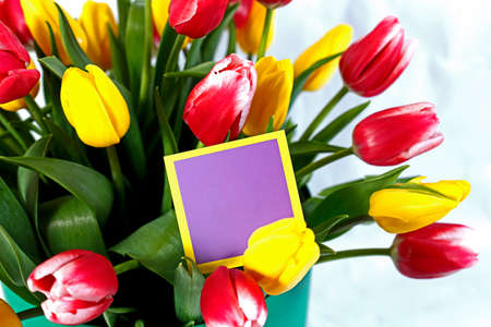 Bright festive flowers in a round box with a postcard on a white backgroundの写真素材