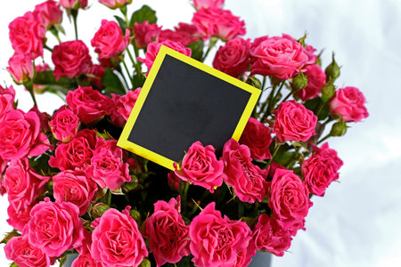 Bright festive flowers in a round box with a postcard on a white background