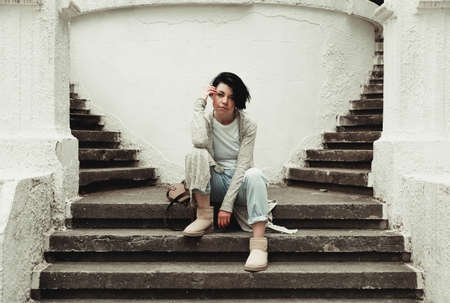 Stylish girl sitting on stone stairsの写真素材