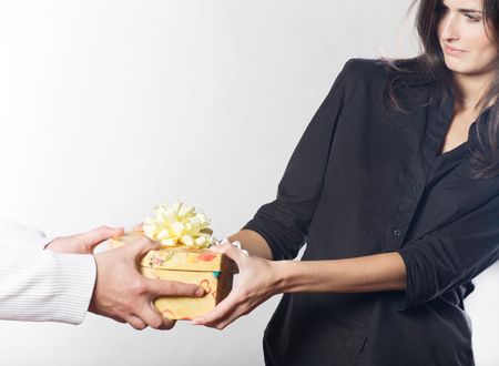 Young woman trying to pull out a box with gift from man's handsの写真素材