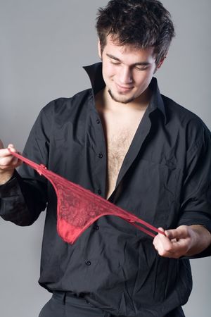 Young man keeping red lingerie, smilingの写真素材