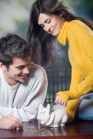 Couple playing with piggy bank, outdoorの写真素材