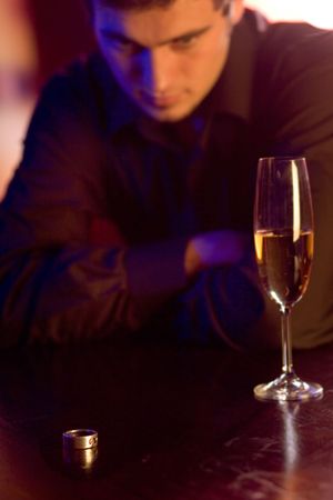 Young puzzled man with ring and champagne glass in restaurant. Focus on the ring.の写真素材