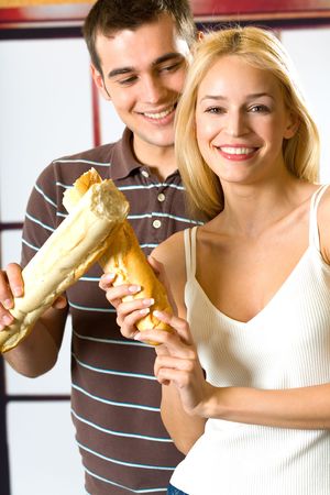 Young attractive happy smiling couple playfully posing with long loaf, indoorsの写真素材