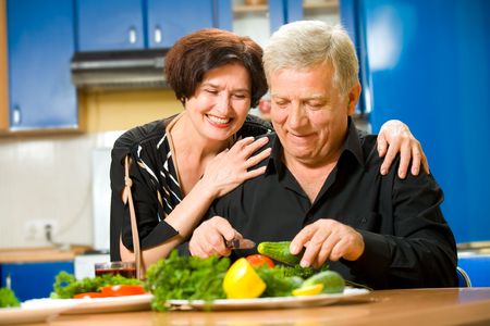 Elderly happy attractive smiling couple cooking at kitchenの写真素材