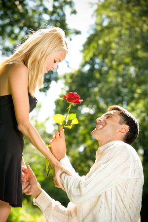 Funny young happy couple with rose, outdoors. Focus on woman.の写真素材
