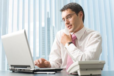 Happy businessman working with laptop at officeの写真素材