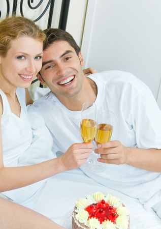 Young couple celebrating with champagne at bedroomの写真素材
