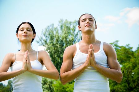 Couple doing yoga moves, meditating or praying together outdoors の写真素材
