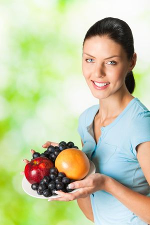 Young happy smiling woman with plate of fruits, outdoorの写真素材