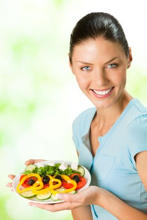 Young happy smiling woman with salad, outdoorの写真素材
