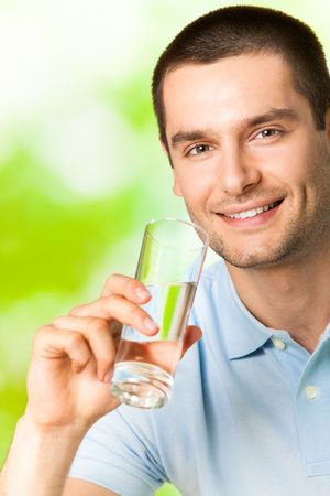 Young smiling man with glass of water, outdoorsの写真素材