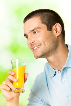 Young smiling man with orange juice, outdoorsの写真素材